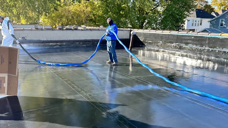 Several Action Wis employees spreading polyurea coating on a rooftop