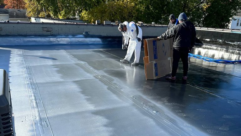An Action Wis employee spreading polyurea coating on a rooftop