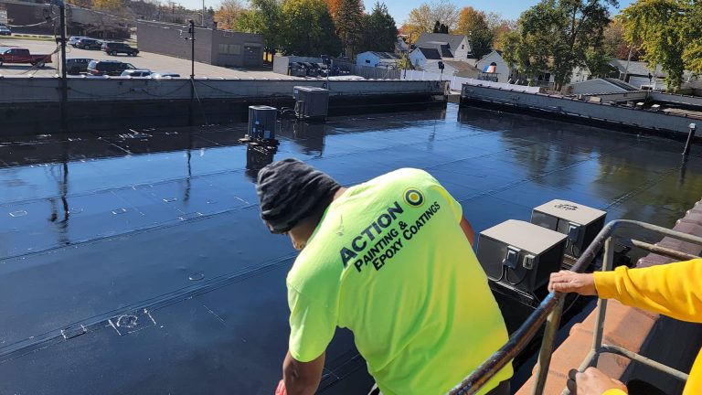 An Action Wis employee spreading polyurea coating on a rooftop