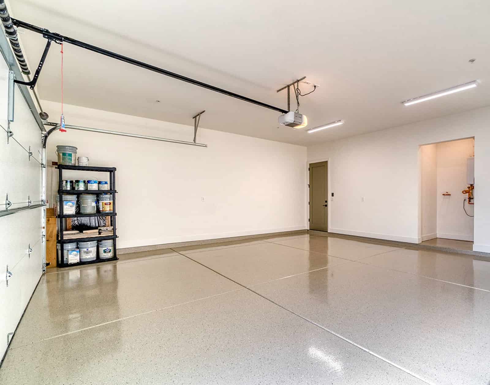 Clean, newly coated garage floor with glossy epoxy finish and paint supplies stored on shelves