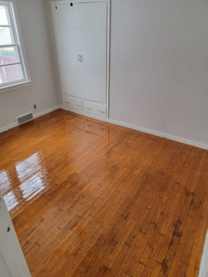 Refinished hardwood flooring in a small Appleton bedroom with white trim and natural light