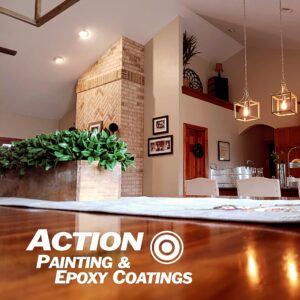 Freshly painted Wisconsin living/dining area with neutral walls, brick fireplace, pendant lights, wood trim, and a succulent centerpiece on a wood table; Action Painting & Epoxy Coatings logo visible.