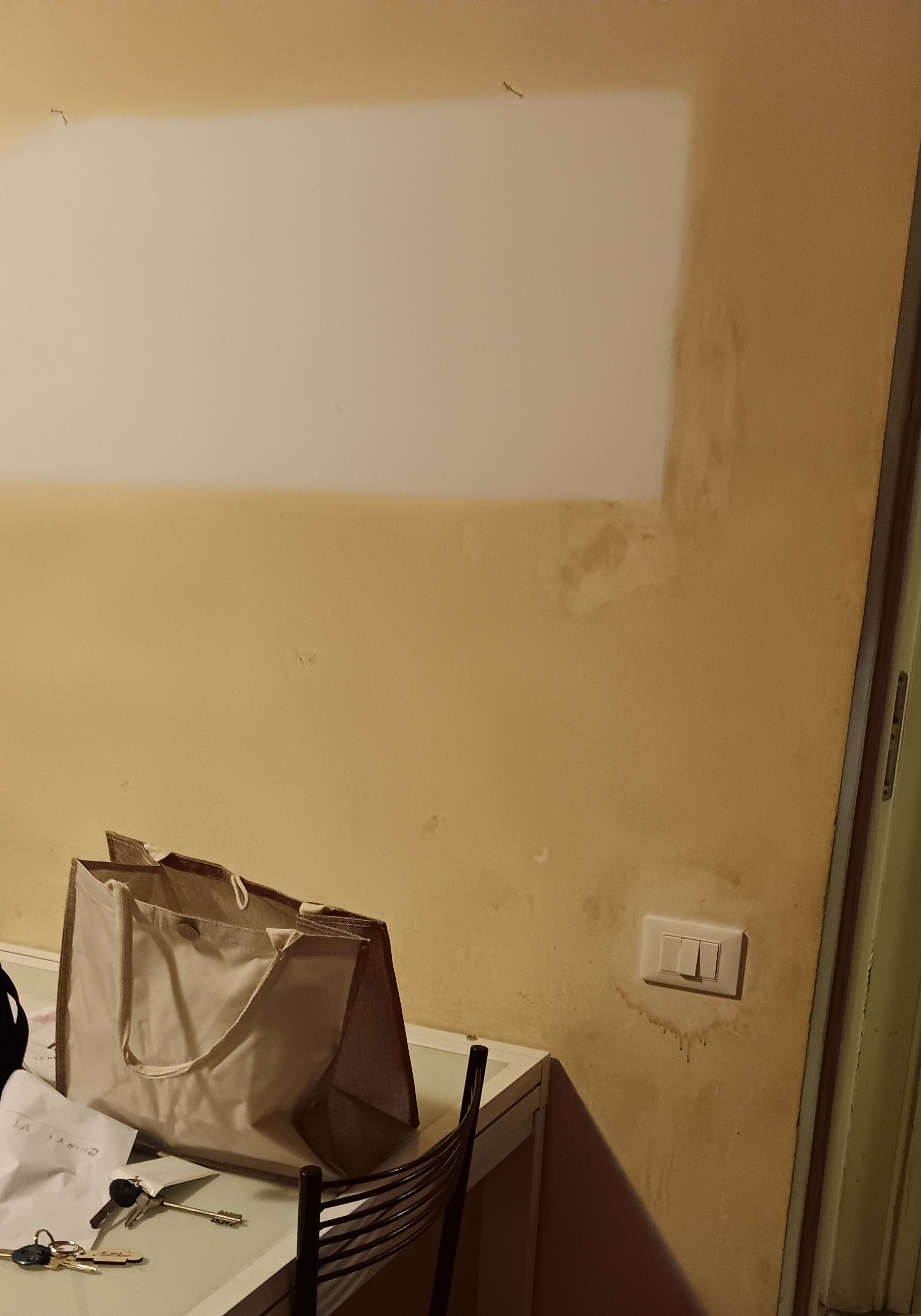 Cigarette smoke stains and yellow tar discoloration on an interior wall, with a clean white painted test patch for comparison.